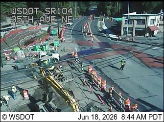 Construction workers and a flagger are present at a roadway work site.