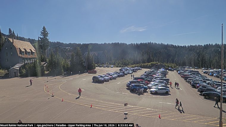Police cars with lights on in a crowded parking lot.