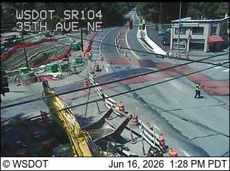 Construction zone with personnel directing traffic and heavy equipment present.