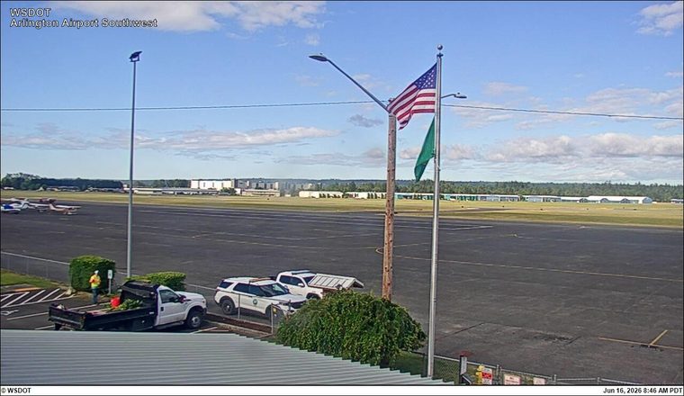 Two police vehicles and a utility truck are parked near a person on the airport tarmac.