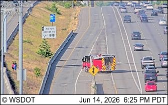 Fire truck on the side of the highway with a person nearby.