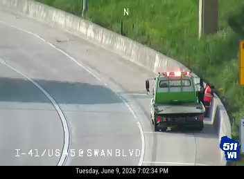Tow truck with flashing lights on the shoulder, possibly assisting a vehicle.