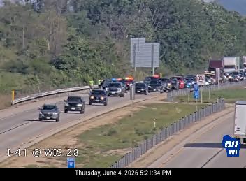 Emergency responders on scene with flashing lights, causing traffic backup.