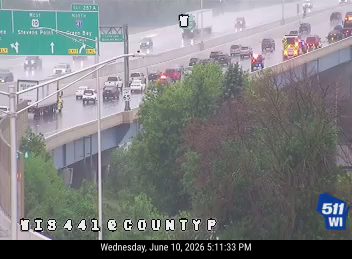 Emergency responders and vehicles are present on the highway during rainy conditions.