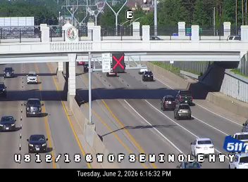 Emergency vehicle with flashing lights on the right shoulder, traffic slowing.