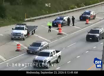 Two police cars with lights on and two officers present in the left lane