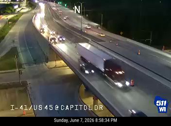 Emergency vehicles and cones on the highway suggest an incident response.