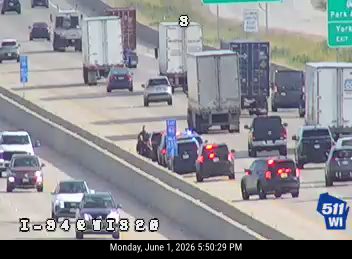 Police and other vehicles stopped on the highway shoulder with emergency lights on.