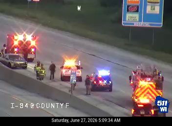 Multiple emergency vehicles including an ambulance with red/blue lights, a fire truck, and police cars on the right shoulder