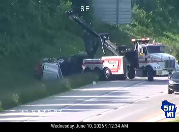 Tow truck and emergency vehicle at scene of overturned vehicle off-road.