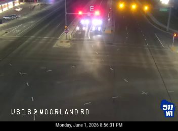 Emergency vehicles with flashing lights are stopped at an intersection.