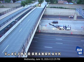 Road work crew with machinery on highway, cones present.