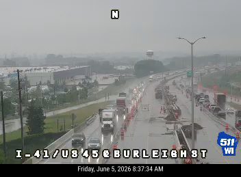 Emergency responders and construction vehicles on the highway with cones and barriers.