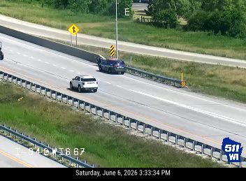 Police car stopped on the shoulder of the highway with its lights on.