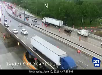 Ambulance and cones on the right shoulder, traffic moving slowly moving.