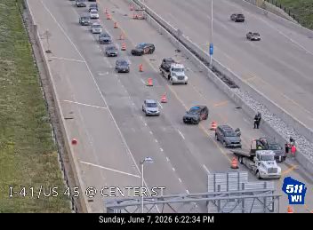 Emergency responders and tow truck assisting vehicle on the side of the highway.