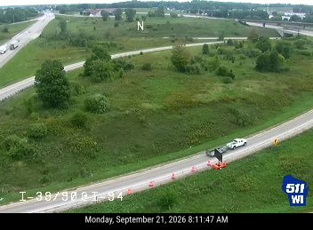 Construction cones and a white pickup truck with a trailer on the right shoulder
