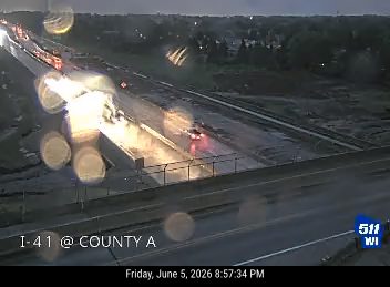 Vehicle crash with bright lights and debris on wet highway.