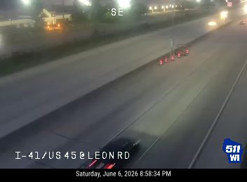Emergency responders with flashing lights and cones on the highway.