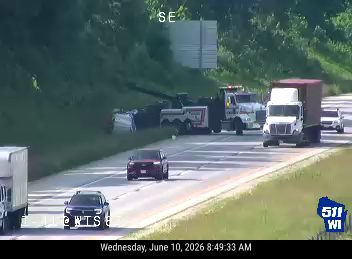 Tow truck and other vehicles stopped on the side of the highway, possibly assisting with an incident.