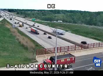 Red truck with trailer on shoulder, possibly responding to an incident.