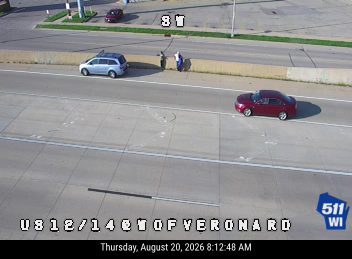 Two people standing on the right shoulder next to a silver SUV