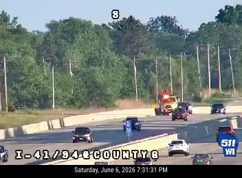 Emergency vehicle and tow truck on the side of the highway.