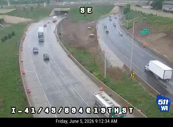 Construction vehicle and workers on the right shoulder of the highway.
