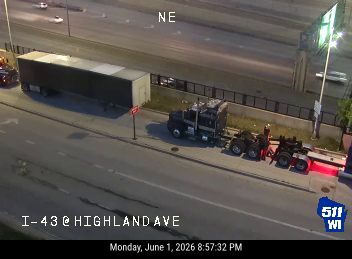 Tow truck and trailer assisting a disabled semi-truck on the highway.
