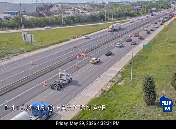 Road work with cones and a truck on the highway shoulder.