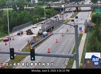 Construction vehicles and personnel present on the roadway, indicating a possible incident or work zone.