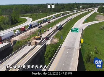 Construction vehicles and personnel on the highway shoulder, likely road work.