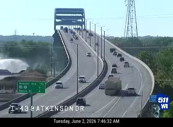 Firefighters spraying water on a fire on the side of the road near the bridge.