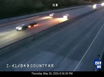 Vehicle appears to have crashed and is on fire on its side with lights on.