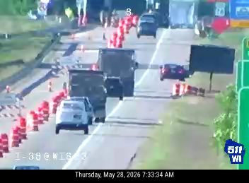 Emergency responders and cones on highway, traffic is moving slowly moving.