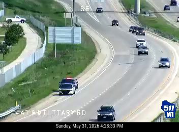 Two police cars are stopped on the shoulder of the road.