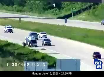 Person standing next to a trailer on the right shoulder