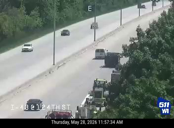 Construction vehicles and personnel on the side of the highway.