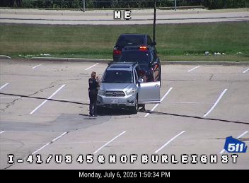 Police officer interacting with occupants of a silver SUV with an open door