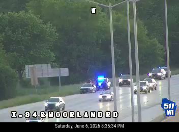 Police cars with flashing lights on the highway, indicating an incident response.