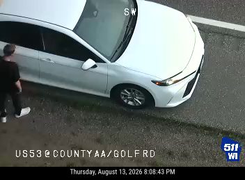 Person standing next to a white sedan on the right shoulder
