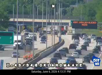 Emergency vehicle with lights on, traffic slowing, right shoulder blocked ahead.