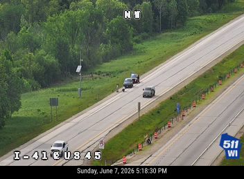 Emergency responders and vehicles are present on the shoulder of the highway.