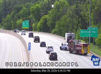 Fire truck and police vehicle on the side of the highway with traffic.