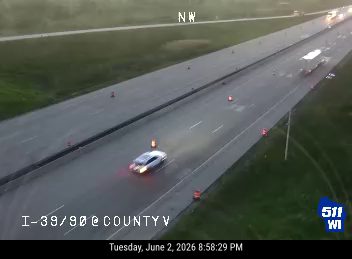 Police car with lights on, cones on highway, indicating a possible incident.