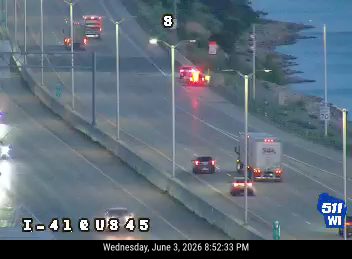 Emergency vehicles with flashing lights on the highway, likely responding to an incident.