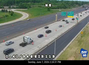 Emergency vehicle and trailer stopped on highway shoulder with cones.