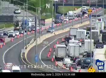 Traffic cones and debris on the roadway, causing lane closures and traffic backup.