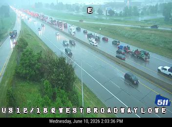 Multiple vehicles involved in a crash on a wet highway, causing traffic backup.