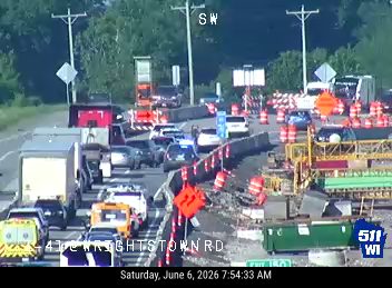 Traffic incident with emergency responders and construction equipment on the roadway.